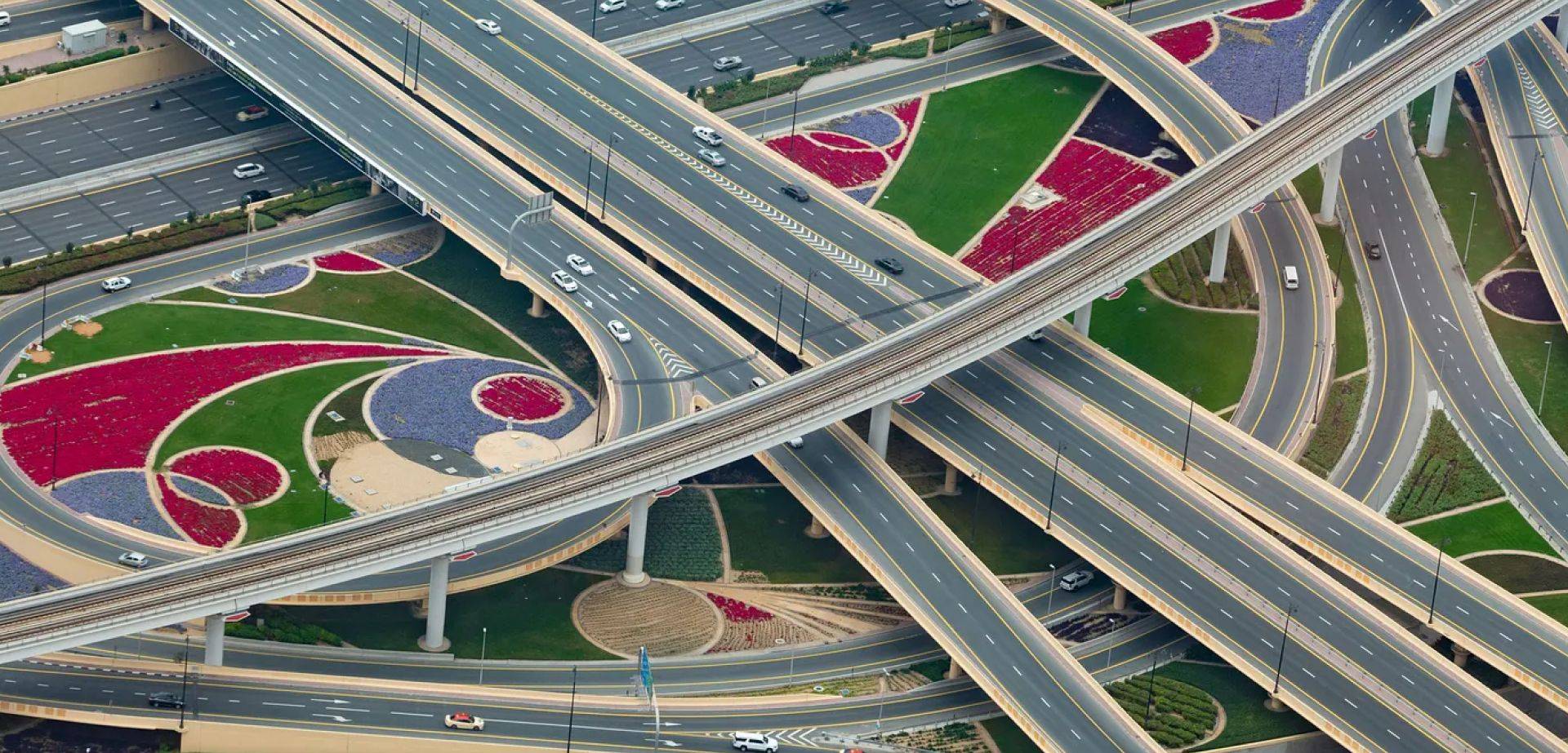 Vista aerea di uno svincolo autostradale multilivello con cavalcavia intrecciati e traffico.